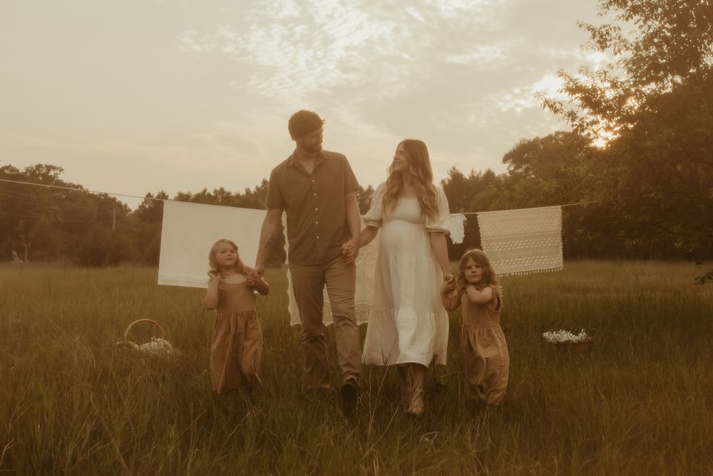 Family watching outdoor movie in rural field at sunset with portable screen setup and blankets spread in grass Pine City Minnesota