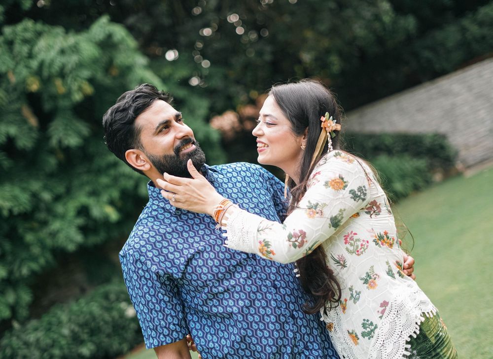 A candid moment of a playful couple wearing floral and polka dot patterns in a garden setting.