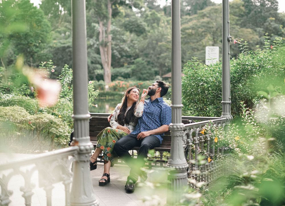 Couple enjoying a peaceful moment together on a park bench surrounded by lush greenery and decorative columns.