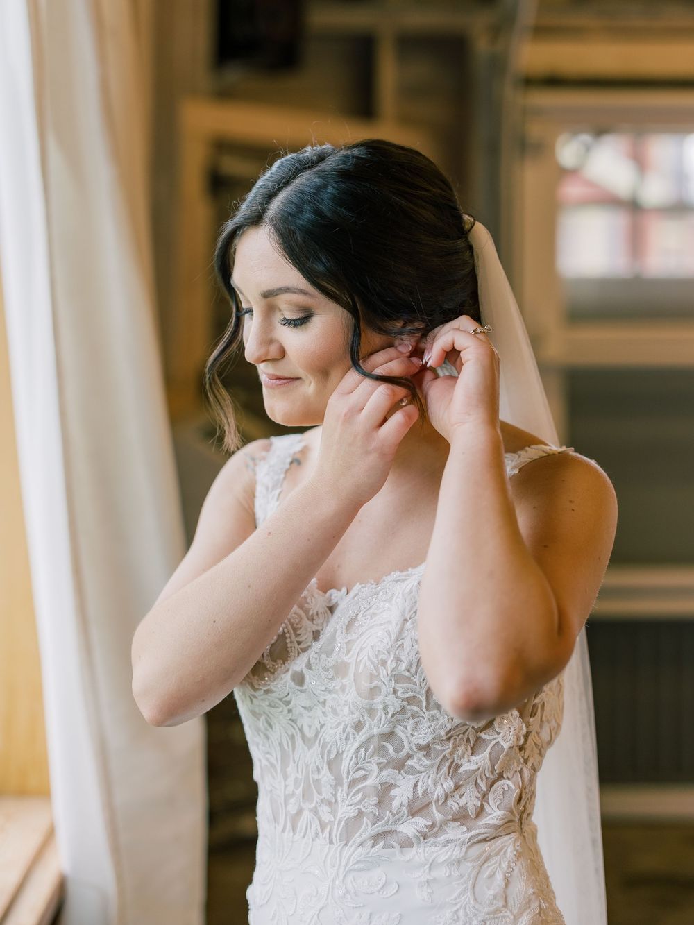Close-up shots of someone adjusting earrings while wearing a delicate lace wedding dress.