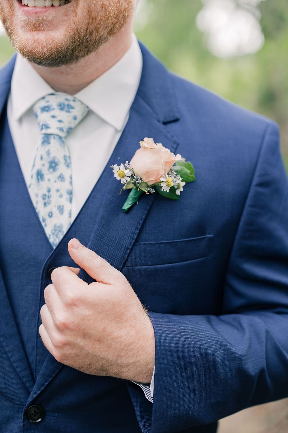 Groomsmen wearing navy suits with light blue floral ties and boutonnières.