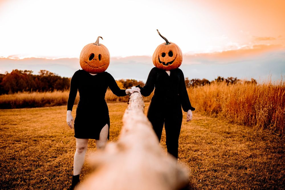 A romantic couple in Halloween pumpkin masks embrace in a misty autumn field at sunset.