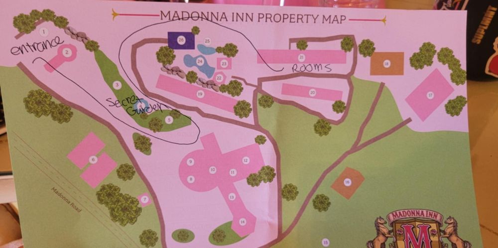 An overhead view of a pink and green property map showing pathways, buildings, and landscaping features.