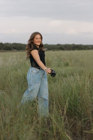 A photographer explores creative movements while shooting in a natural grass field setting.