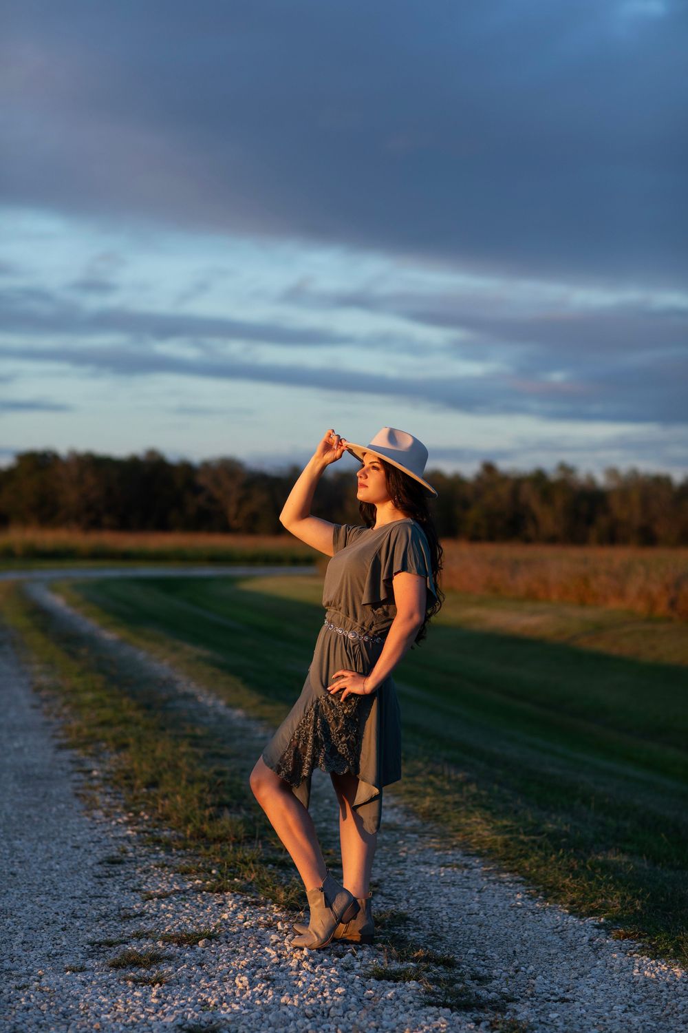 Artistic sequence of a dancer performing graceful movements on a gravel path at sunset with dramatic cloudy skies.