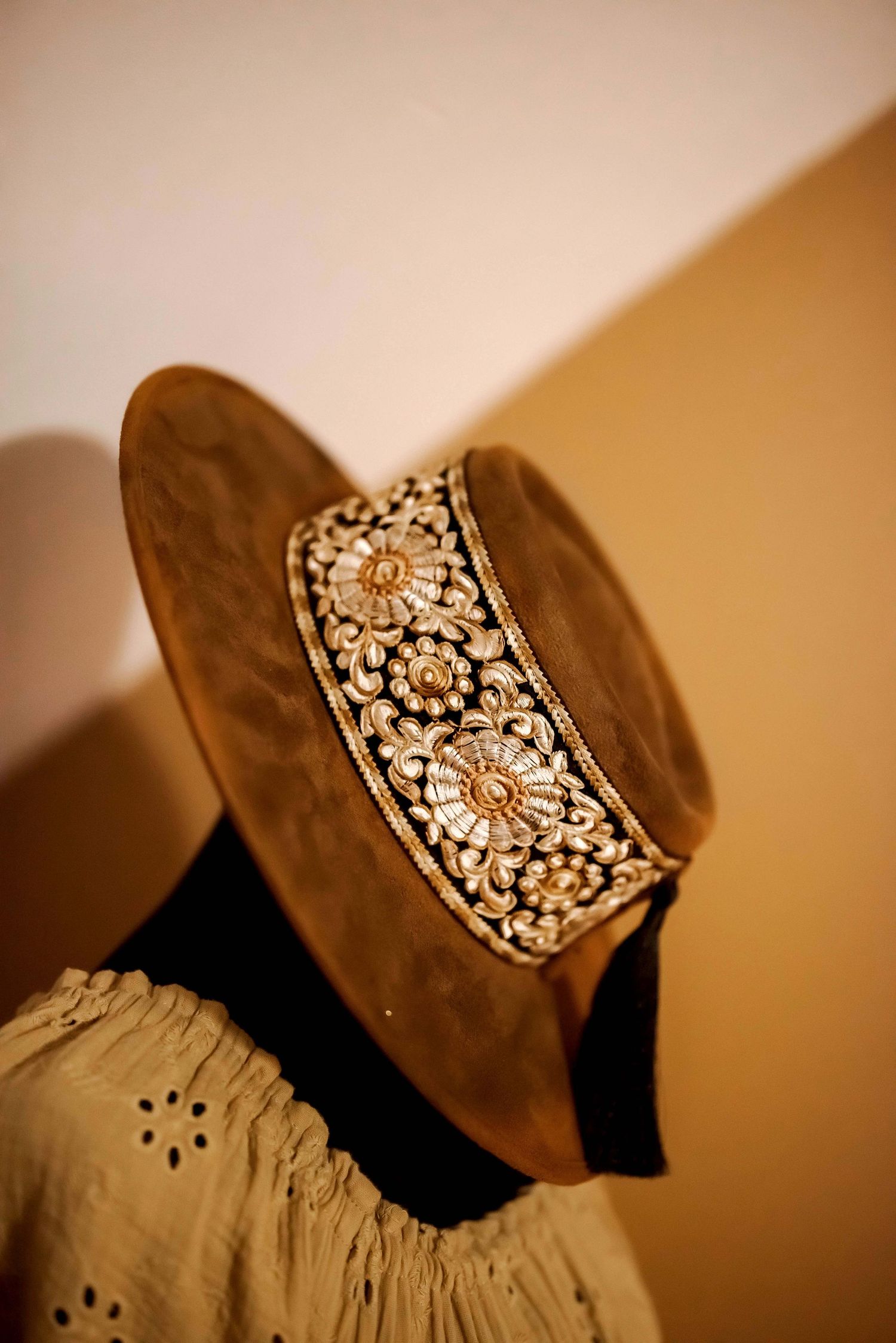 A jeweled crown brooch is displayed from different angles in warm sepia lighting against a dark background.