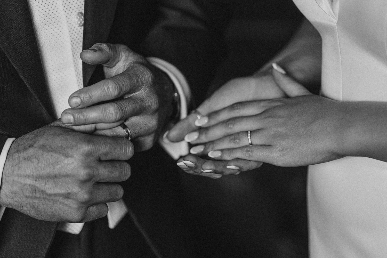 Black and white photo of hands exchanging wedding rings during a marriage ceremony.