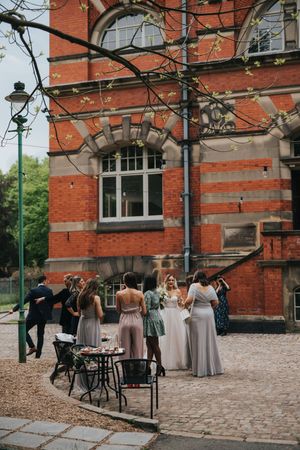 Group gathered outside historic red brick building with arched windows and vintage street lamp on cobblestone courtyard.