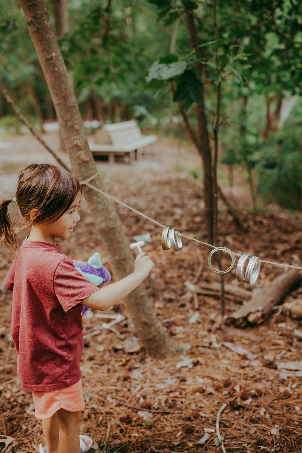 Child in red shirt plays with tin can telephone string in autumn forest setting. Whitney Popp, Arizona photographer