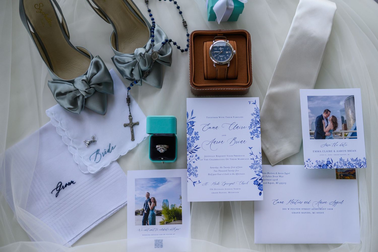 Wedding details flatlay featuring shoes, rings, invitations, and photographs on white background.