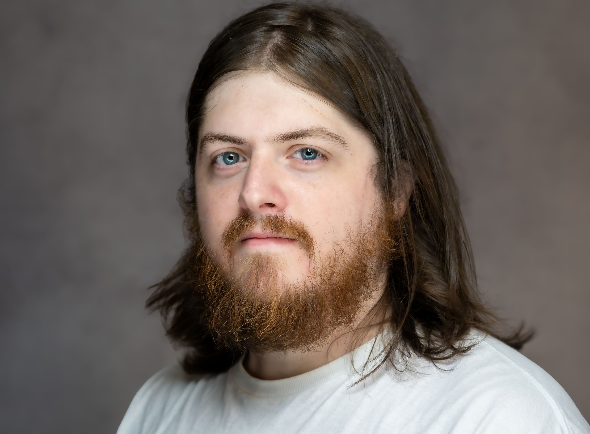 A professional headshot sequence shows a bearded man with long hair making various facial expressions against a gray background.
