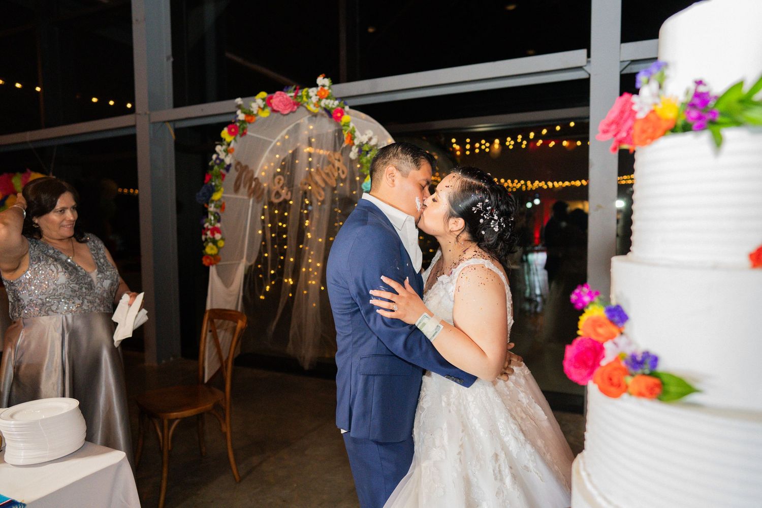 Wedding couple on tree-lined path with flowing veil in romantic pose.