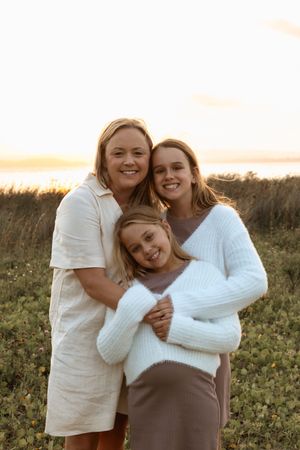 Three outdoor portrait photos show a loving family enjoying a sunset moment in a rustic field setting.