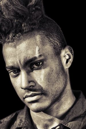 Dramatic monochrome portrait of an individual with intense gaze against dark background.
