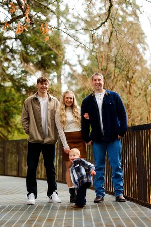 A group of people standing together on a wooden walkway surrounded by autumn trees in a natural outdoor setting.