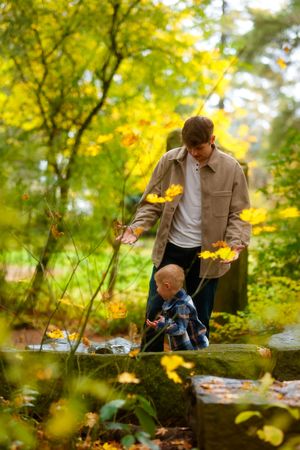 Two people enjoying a fall day together outdoors among yellow autumn leaves in a natural setting.