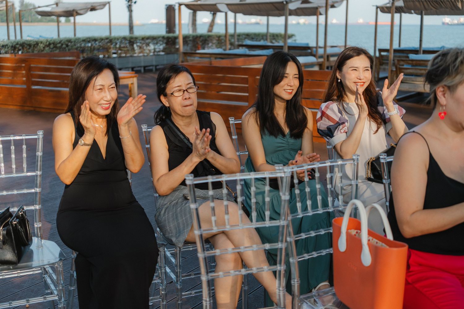 Party guests enjoying a sunset cruise on a yacht deck with cocktails and casual attire.