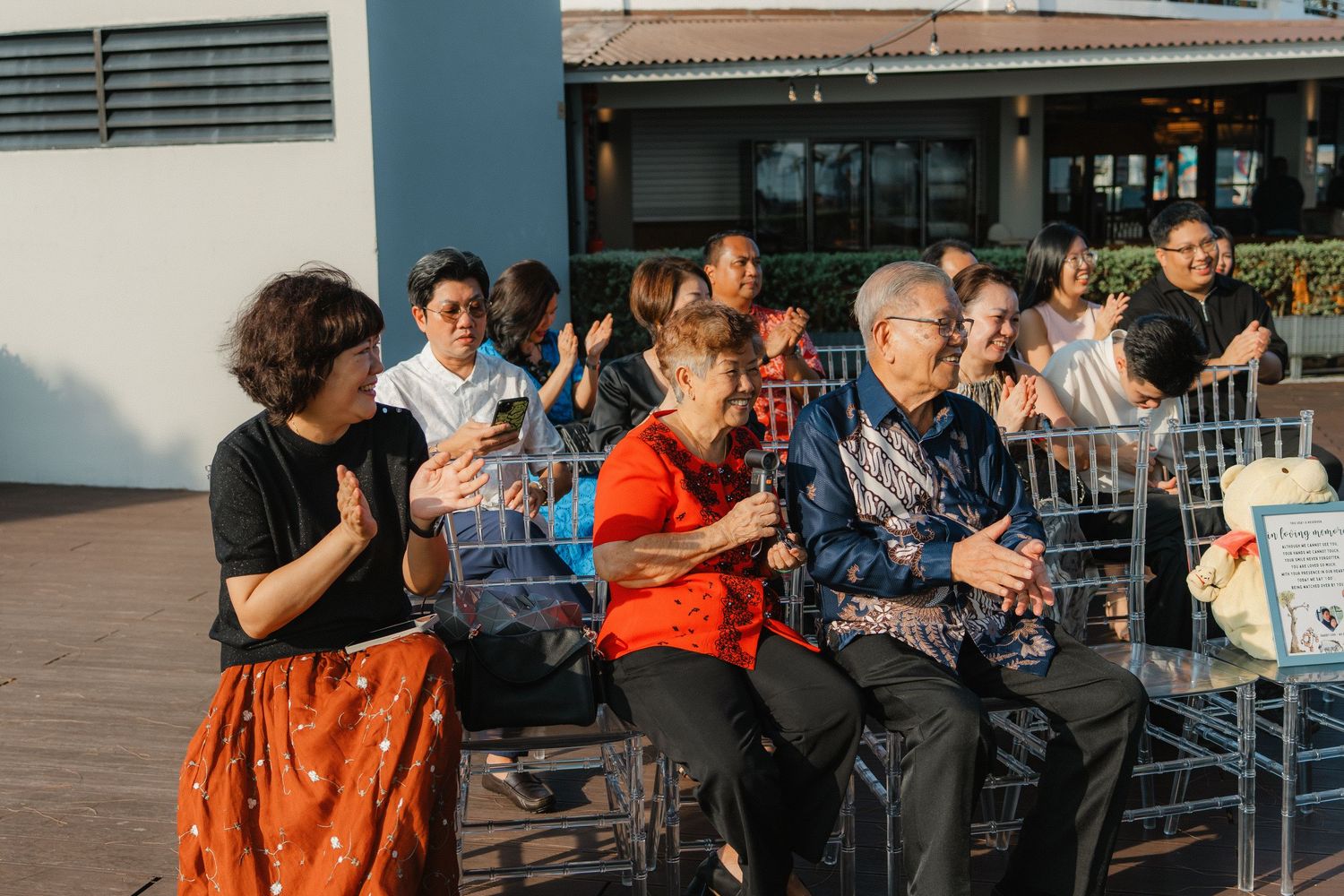 People gather at an outdoor patio area under blue skies and modern architecture.
