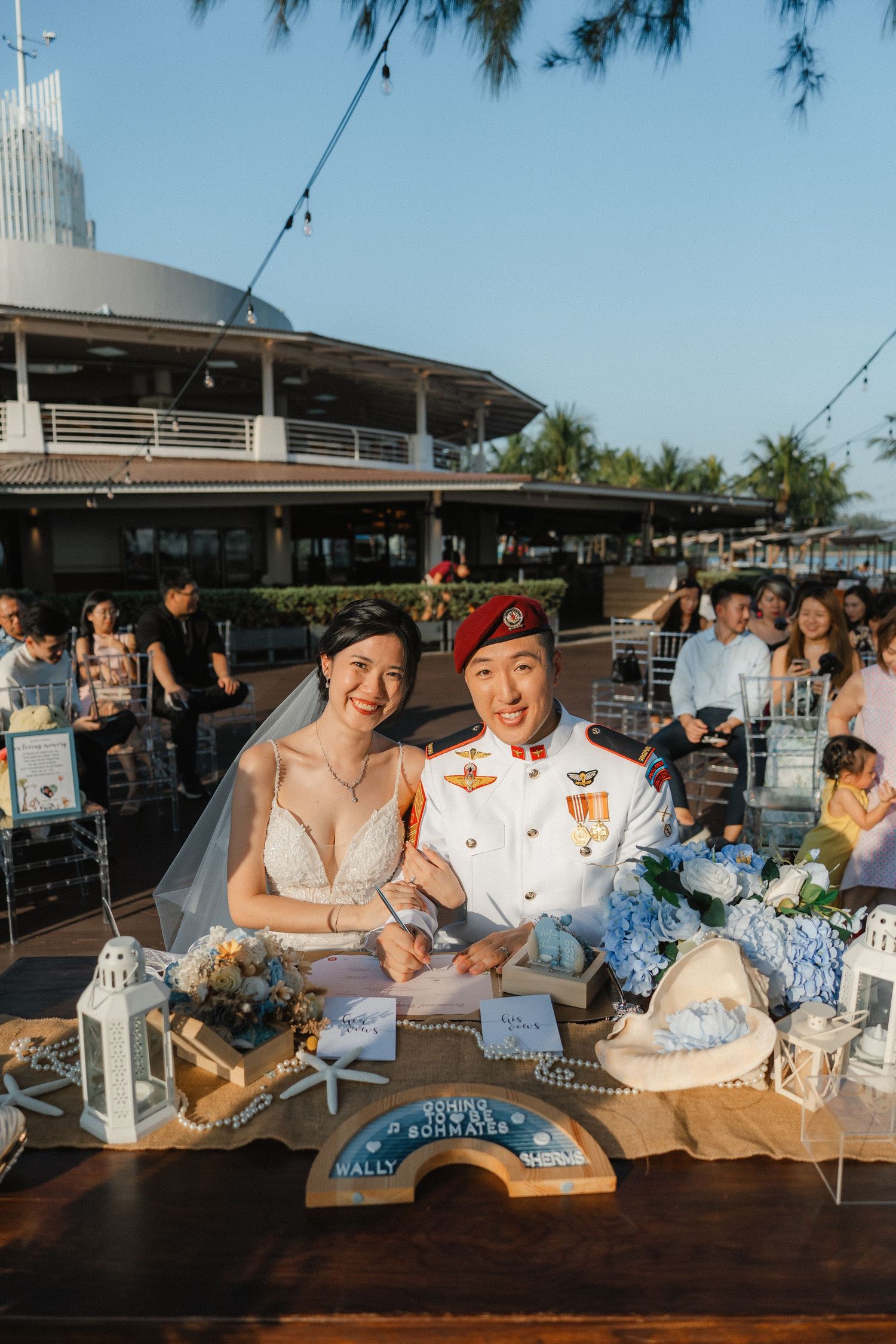 Wedding reception guests enjoying a casual outdoor gathering at tables in the late afternoon sunlight.