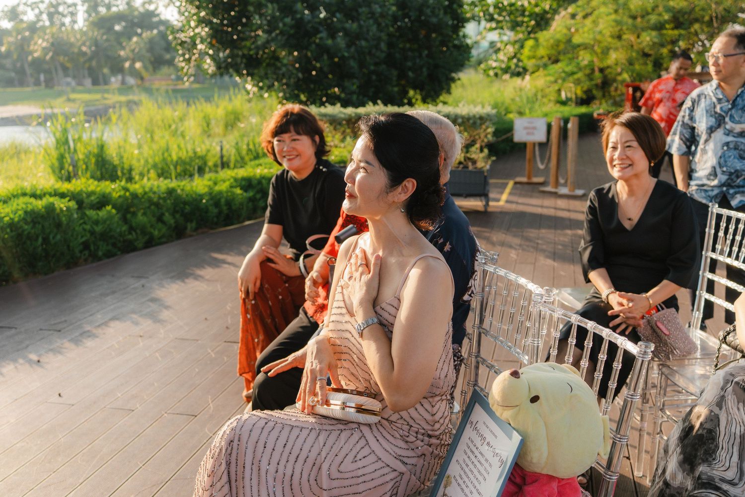Wedding guests seated at outdoor reception tables in a lush garden setting.