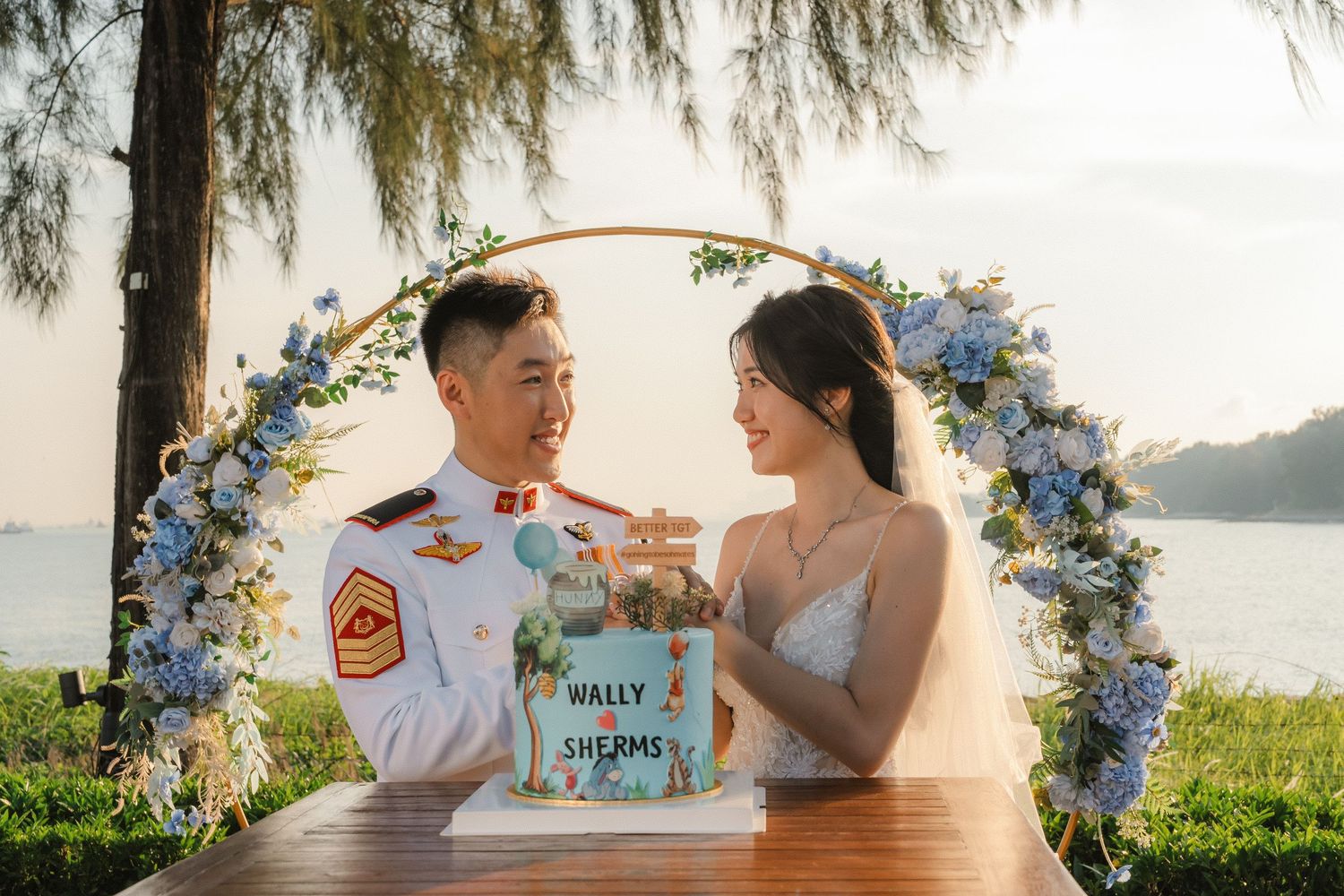 A series of romantic sunset photos showing a couple celebrating their wedding day by the ocean with blue floral decorations.