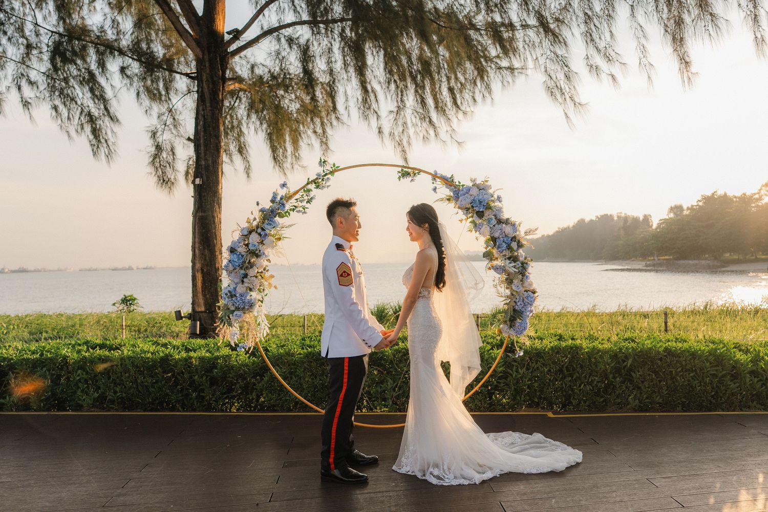 Romantic sunset wedding ceremony overlooking calm waters with floral arch and seating.
