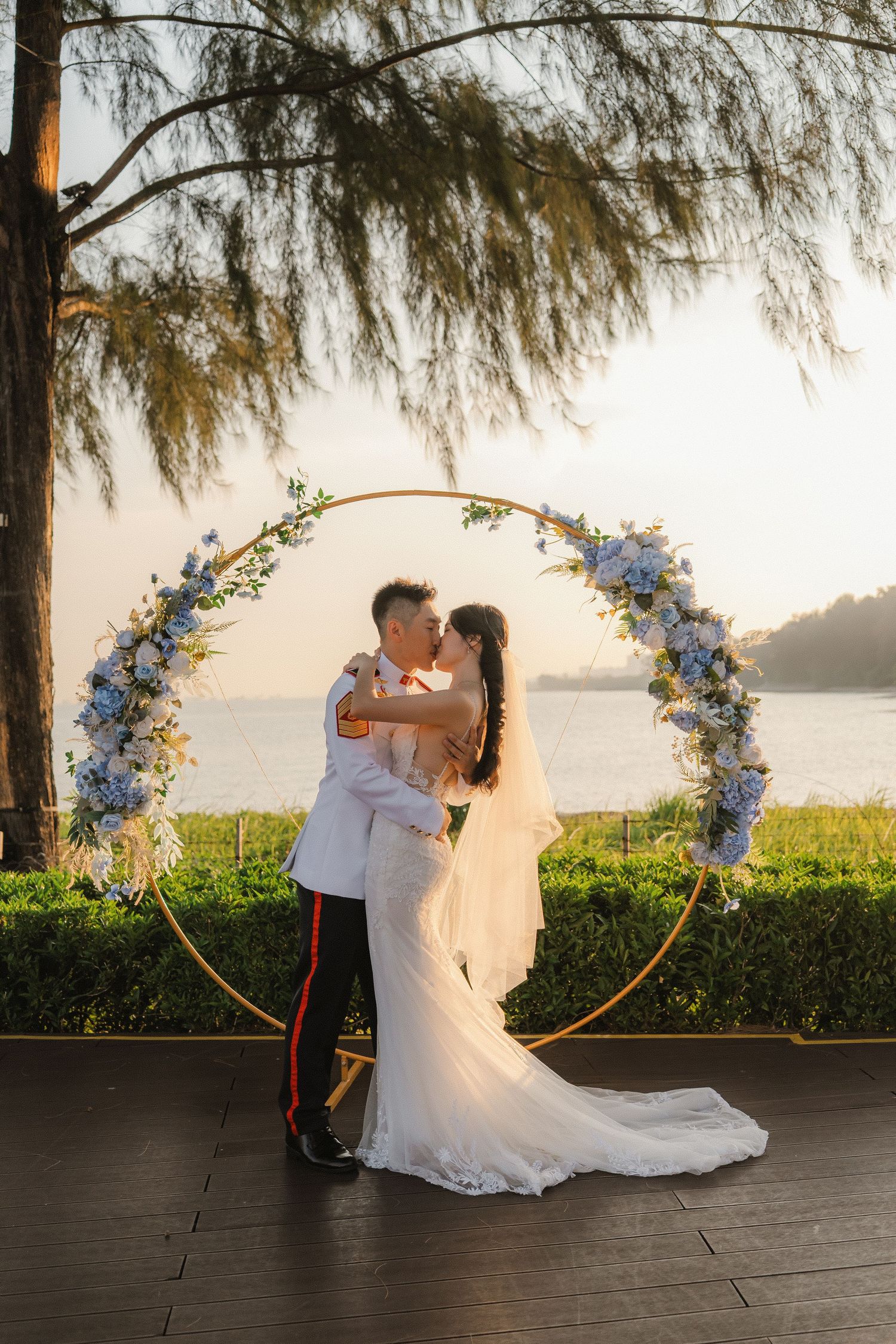 Romantic wedding portraits at sunset with ocean backdrop and floral arch decorations.
