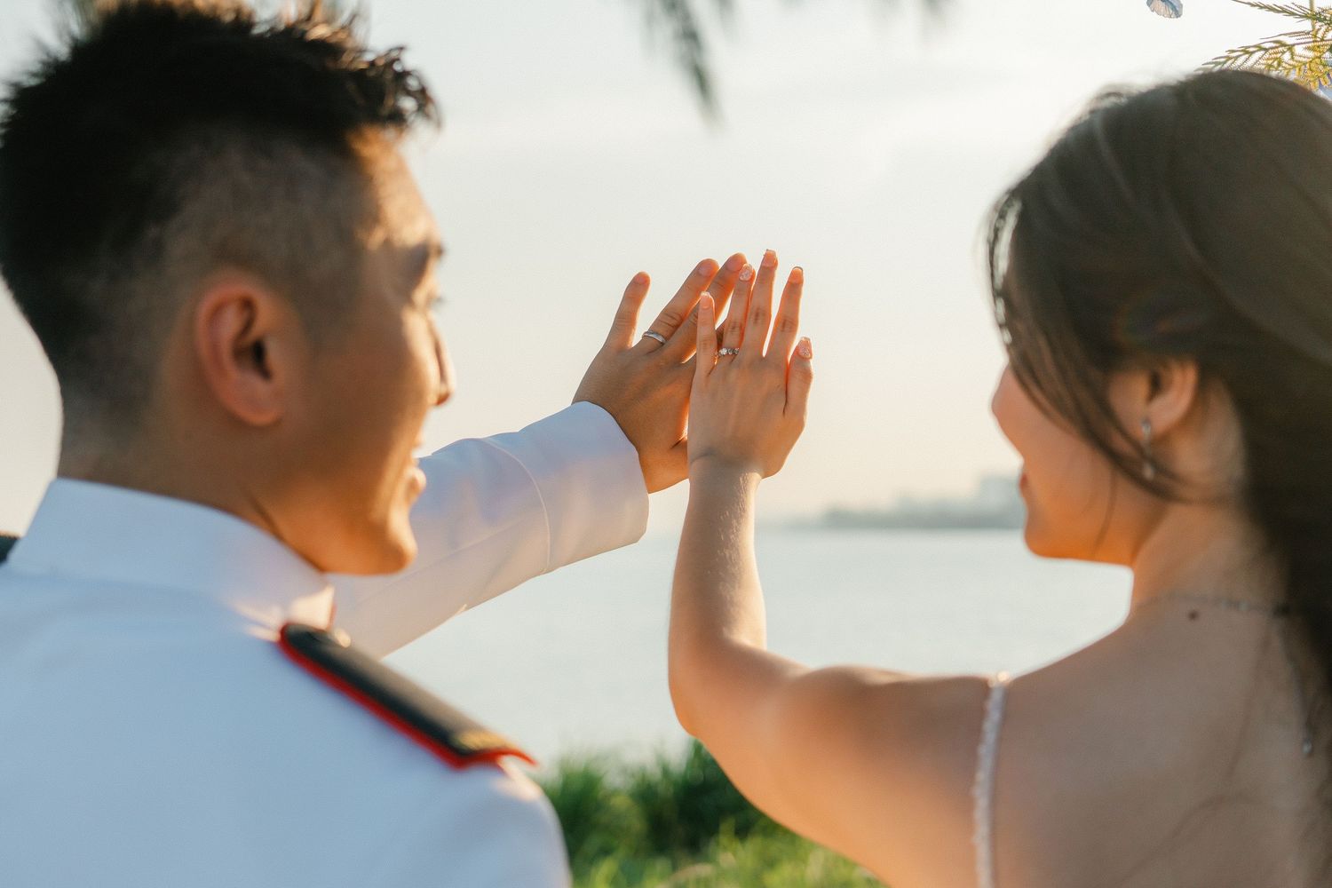 Silhouetted wedding couple share intimate moment during golden hour by the water.