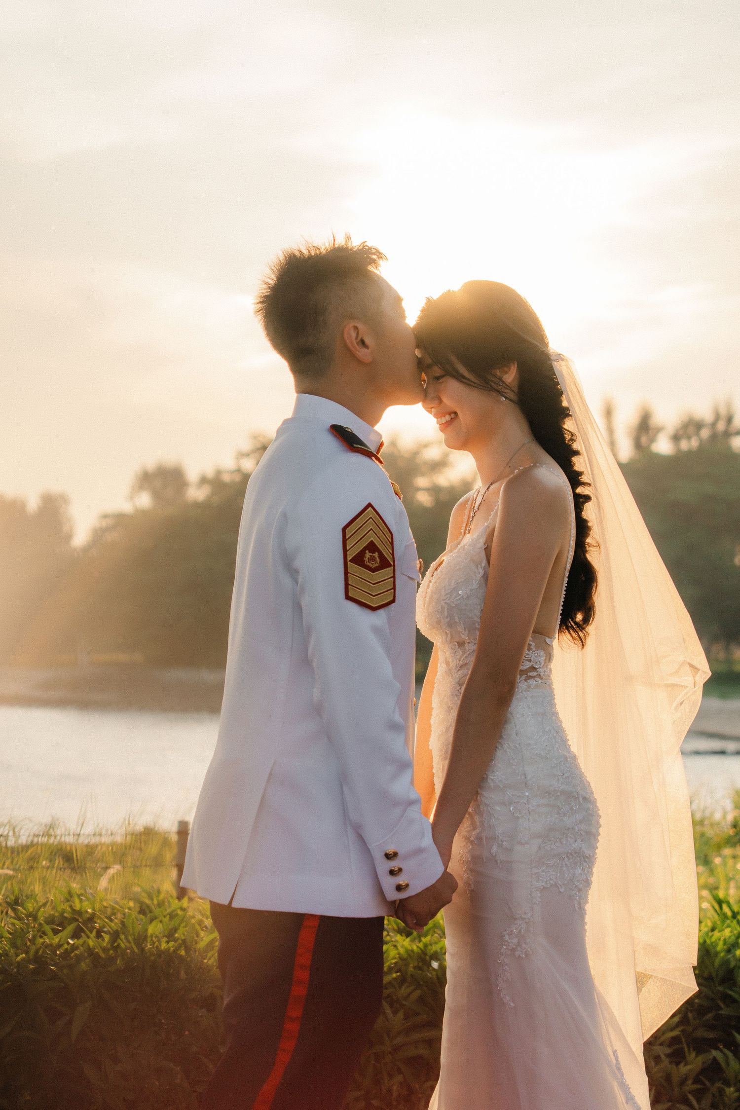 Beautiful sunset wedding portrait captured against glowing sky by the waterfront.