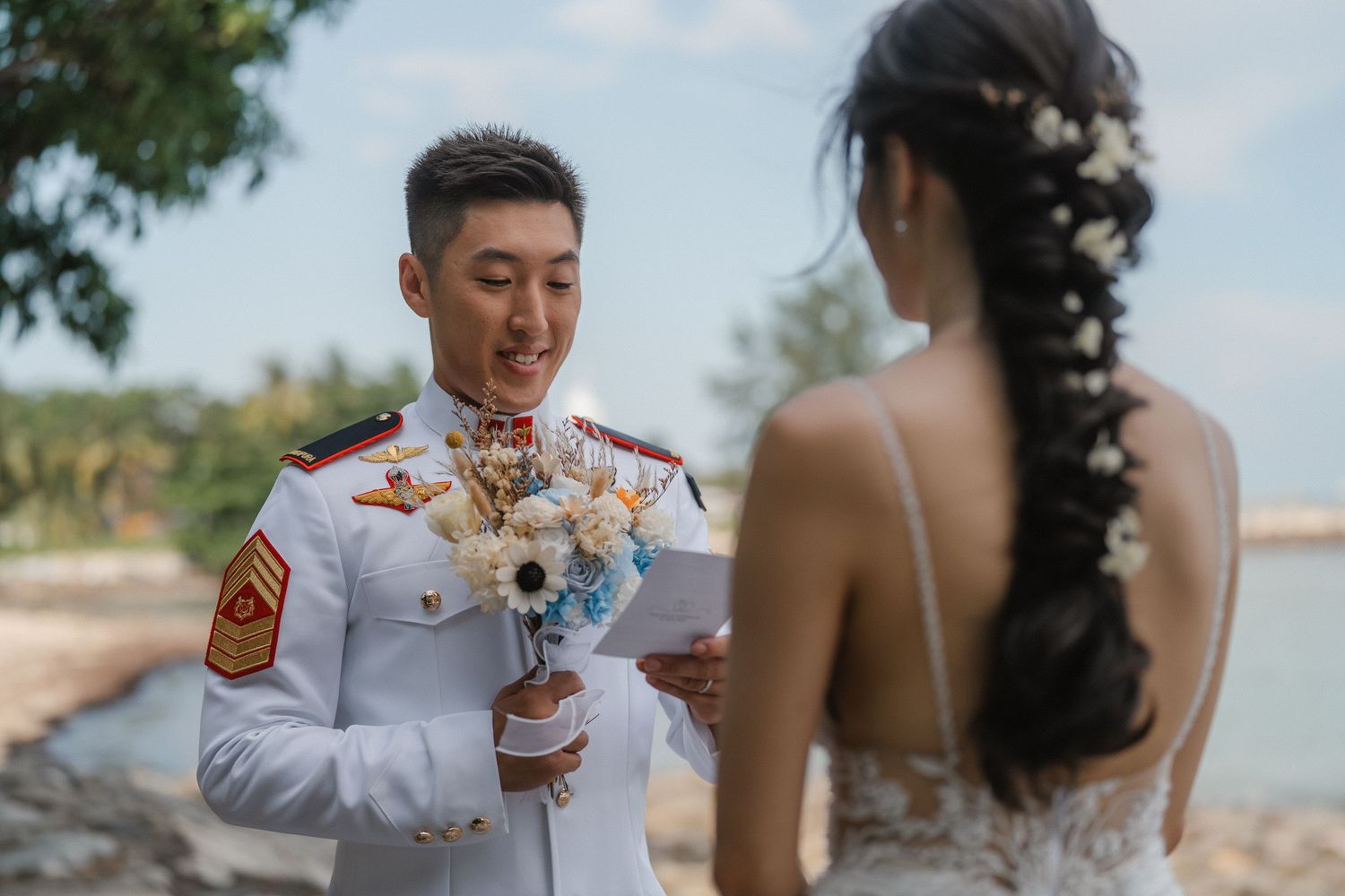 A wedding couple sharing a toast with festive drinks on a scenic beach.