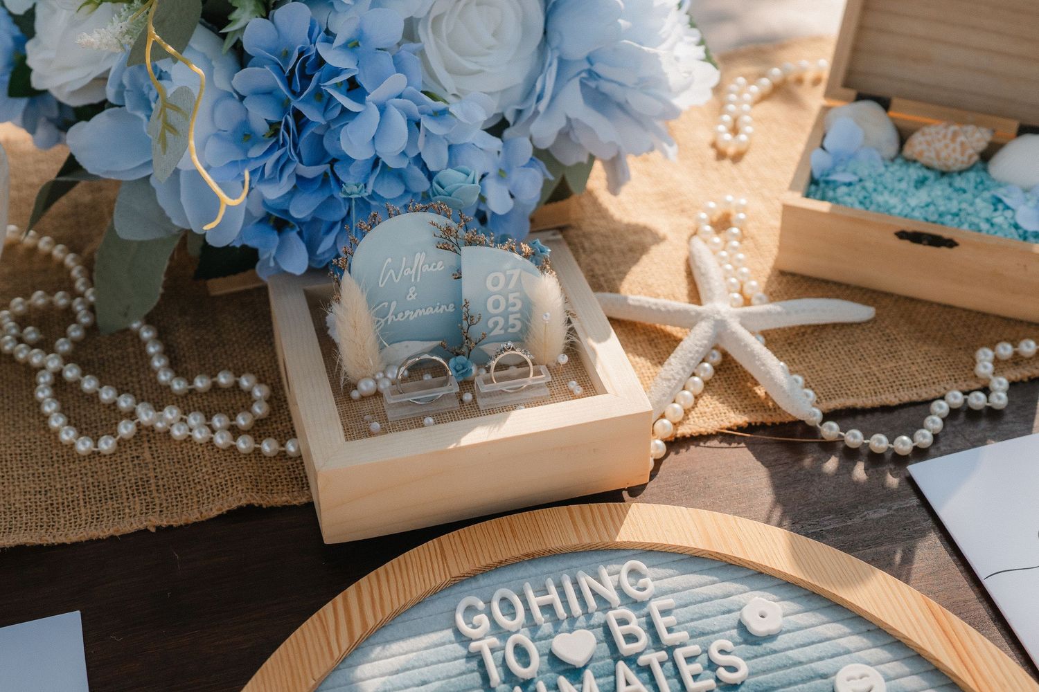 A beach-themed wedding decor featuring blue hydrangeas, pearls, starfish decorations and wooden signage.