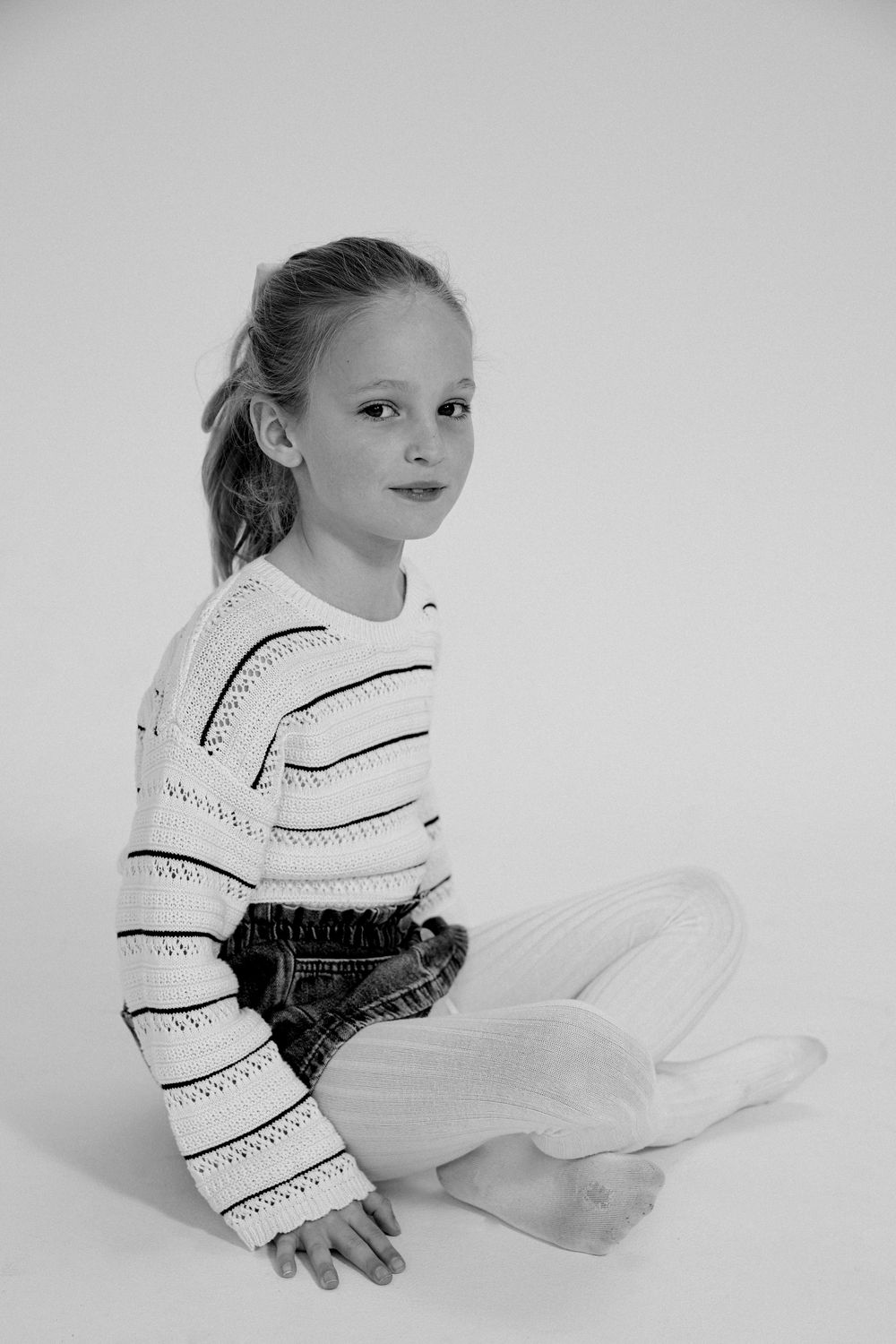 Child wearing a patterned white dress in various graceful poses against a light background