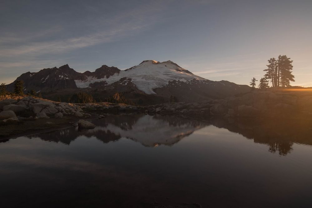 Dramatic mountain landscape at sunset with golden light illuminating rugged peaks and valleys in the wilderness.