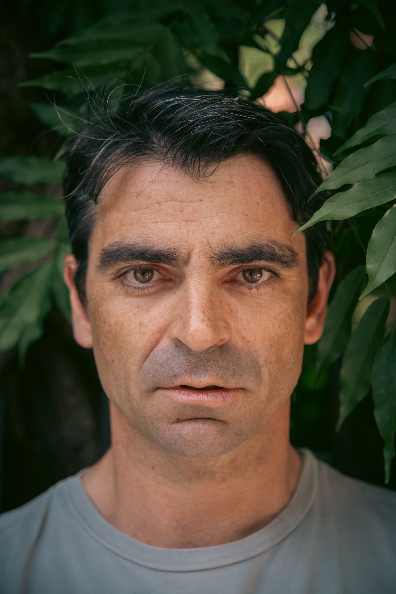 Portrait of a person against a green leafy background.