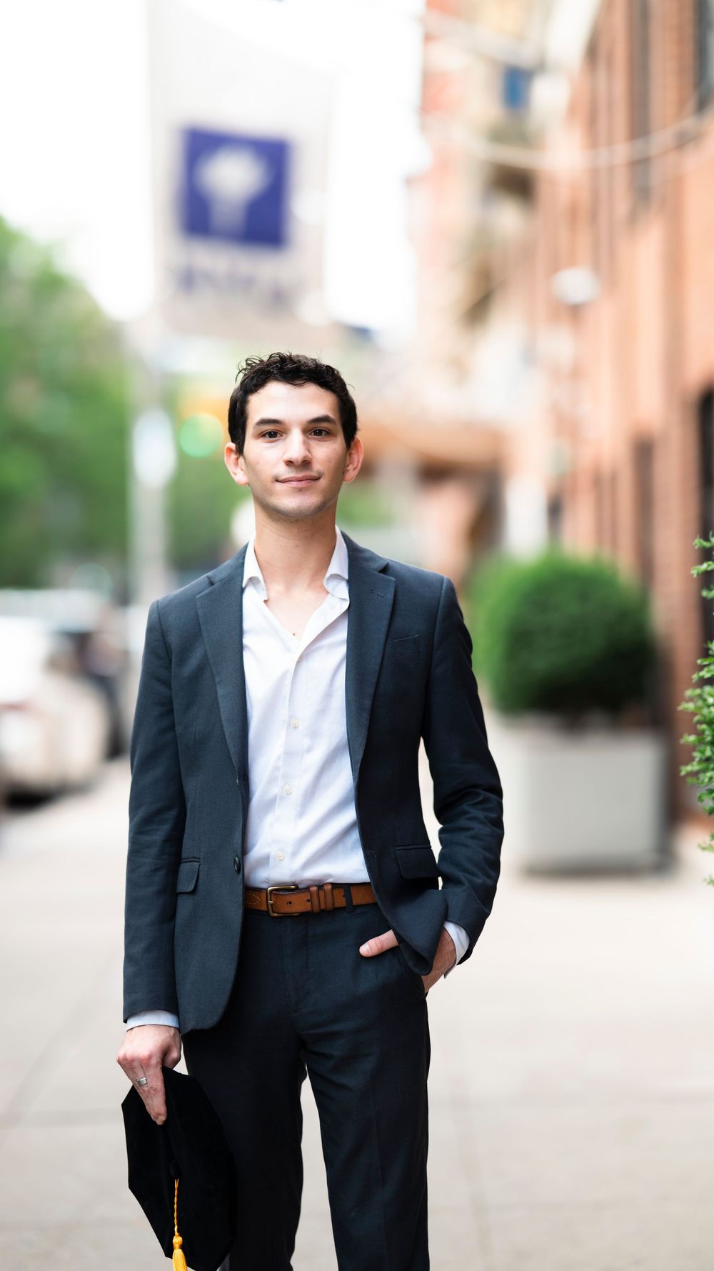 Professional wearing a dark business suit and white shirt walks confidently on a city sidewalk.
