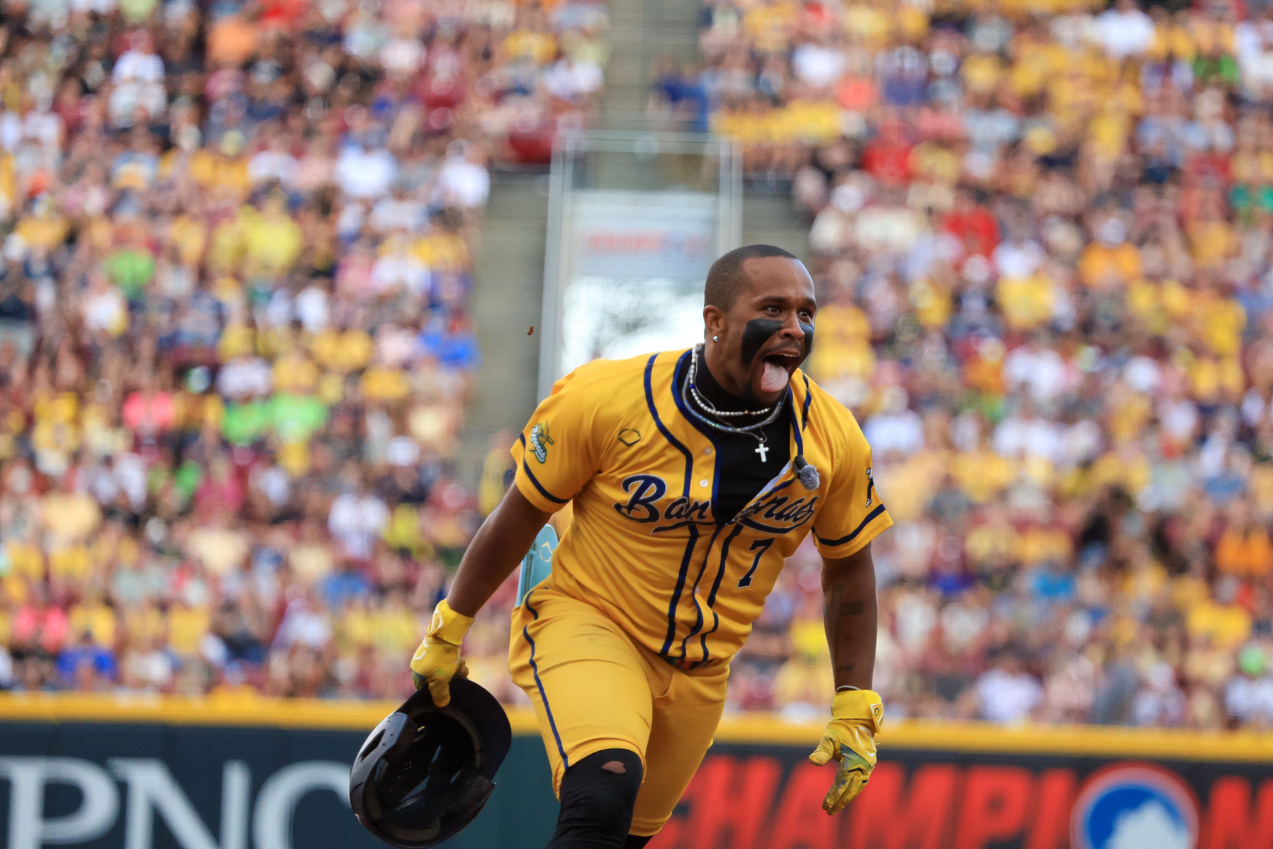 Baseball player in gold uniform celebrates on field before packed stadium crowd.