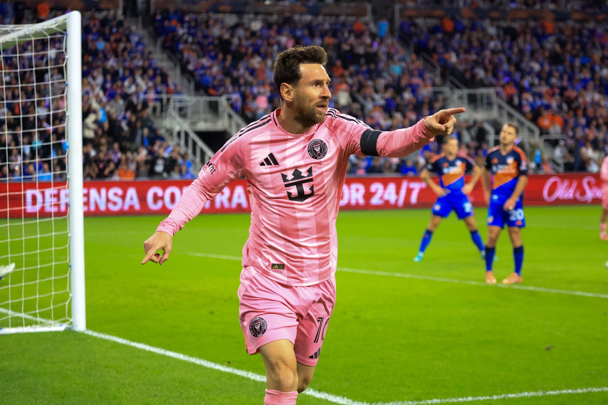 A goalkeeper in pink uniform dives to make a save during a professional soccer match.