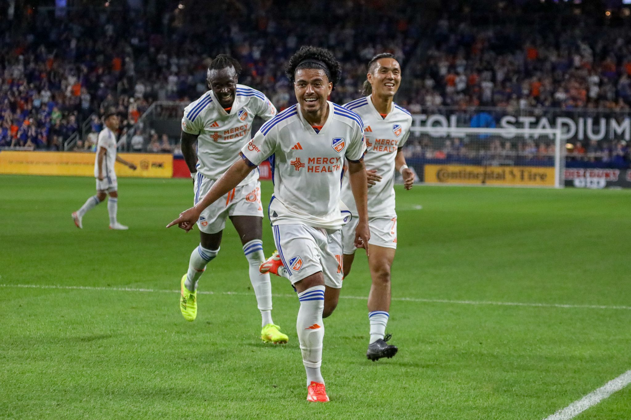 Soccer players celebrate on the field during an intense match at a packed stadium.