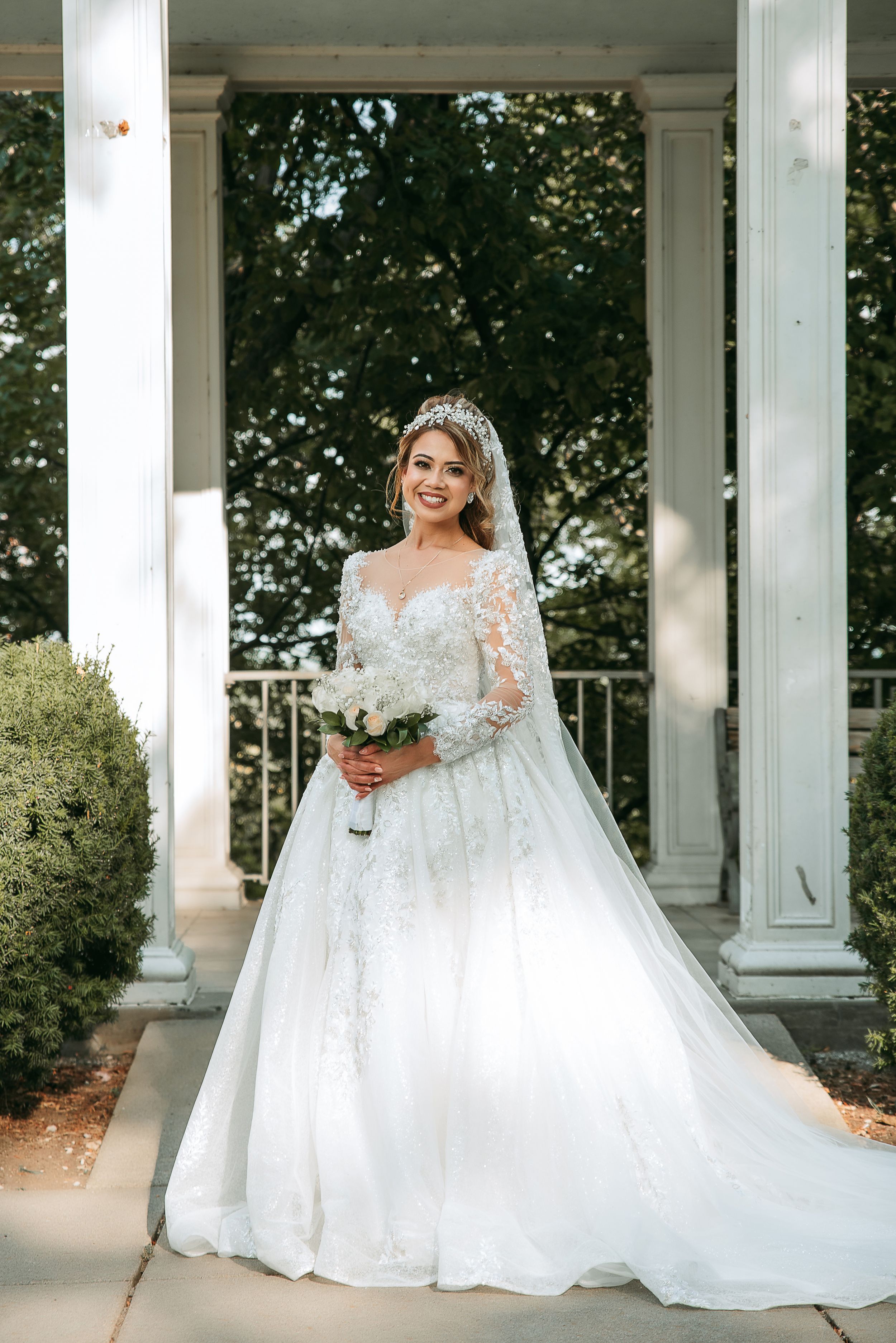Elegant bridal portraits showcasing a white lace wedding gown with long sleeves under a columned pavilion.
