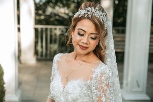 Close-up wedding photography details of a lace veil and ornate crown against white columns.