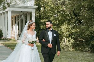 Wedding couple walking together along a columned walkway surrounded by greenery.
