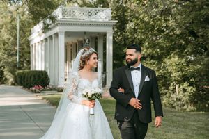Romantic wedding photos of couple strolling beneath an elegant white colonnade.