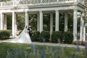 Architectural wedding photography featuring a classical white colonnade and landscaped grounds.