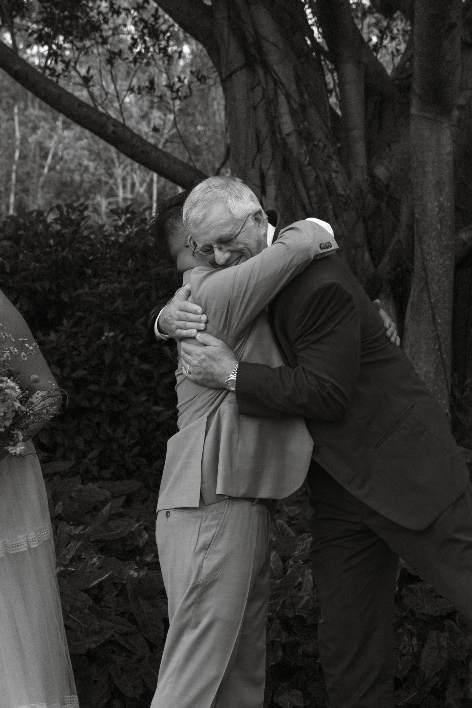Black and white sequence shows groomsmen embracing during wedding celebration.