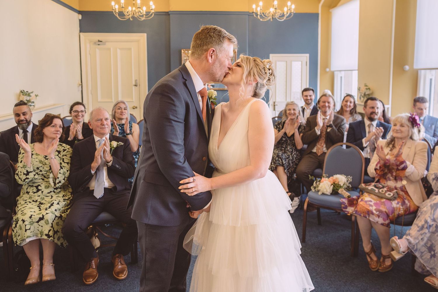 A romantic first kiss at a wedding ceremony as guests look on and applaud at Ipswich Town Hall