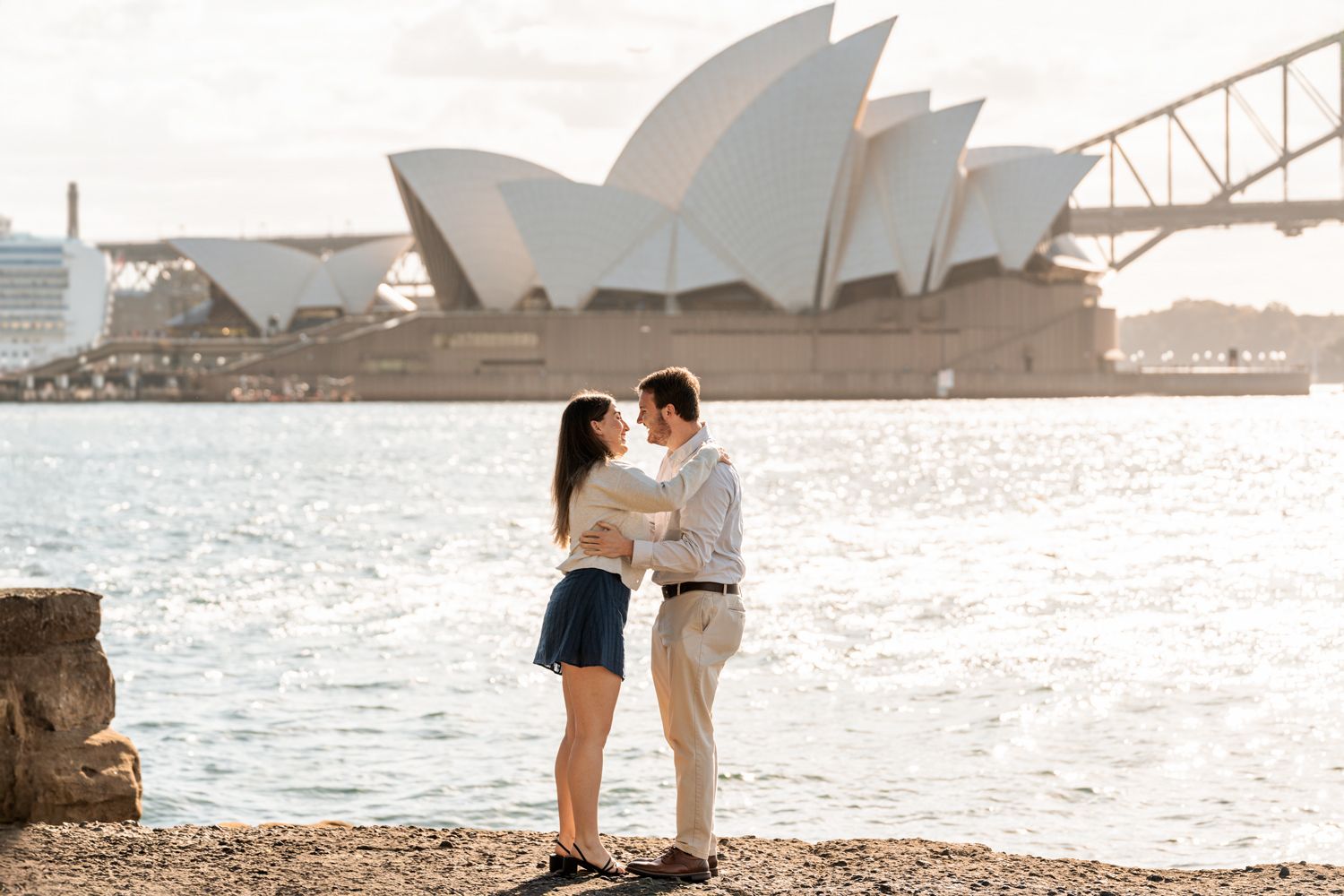 a man and a woman are hugging and kissing after a man proposed during a secret proposal photoshoot in Sydney