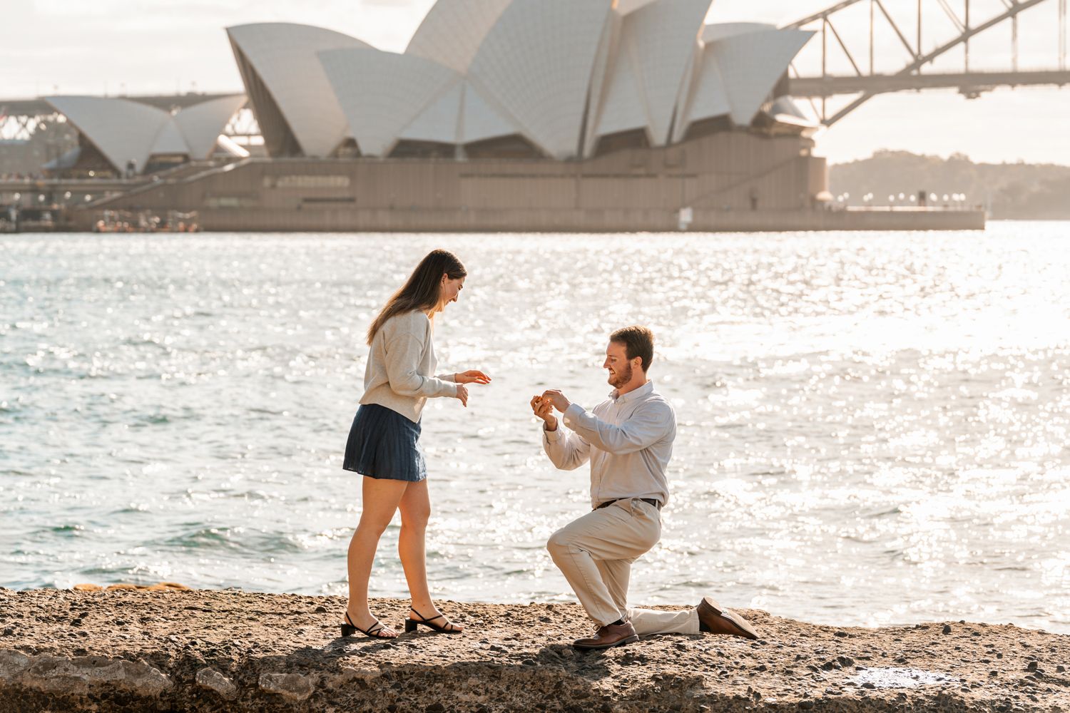 man kneeling in front of a woman to propose her during secret proposal photoshoot in Sydney
