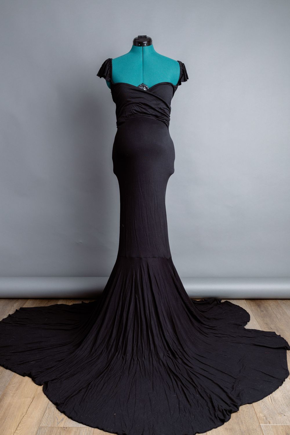 Dramatic black mermaid gown with long train displayed on dress form. Can be used for maternity.