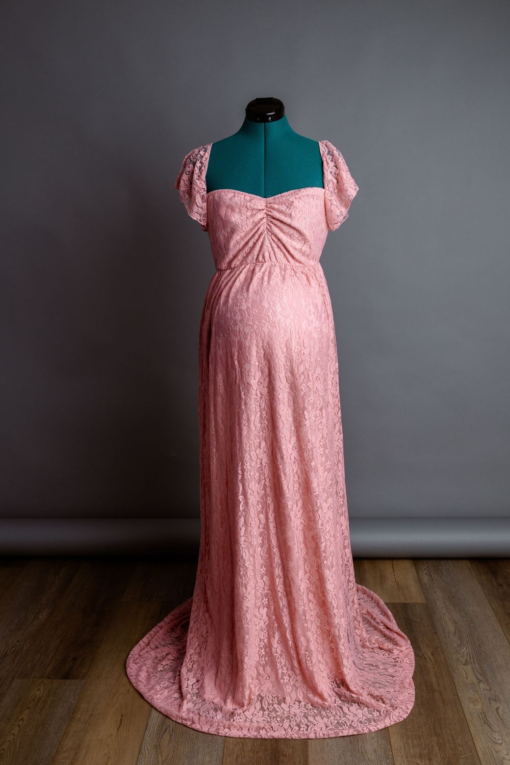 Blush pink lace maternity gown with sweetheart neckline on dress form.