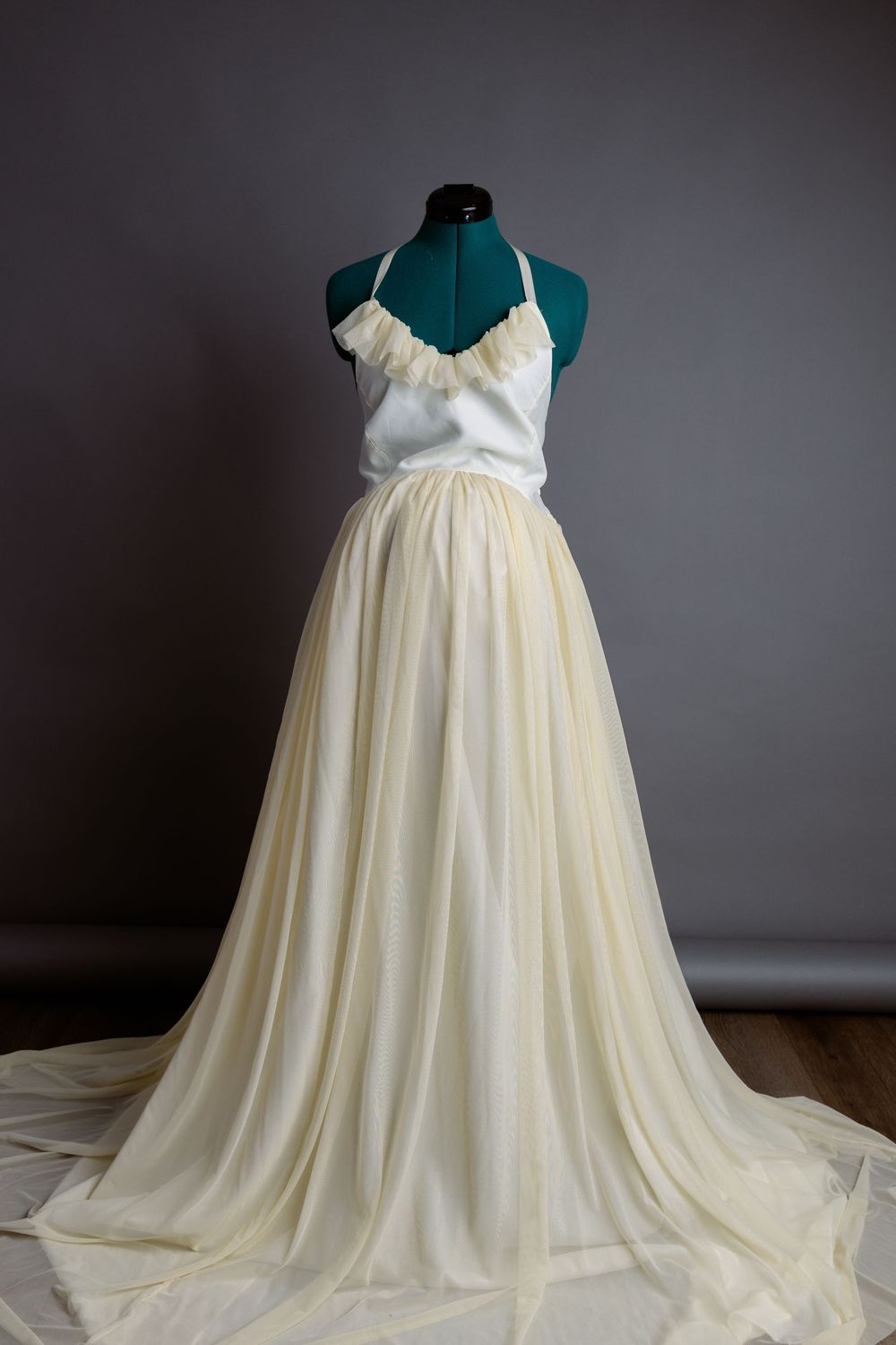 Pale yellow halter-neck maternity gown with flowing skirt on dress form.